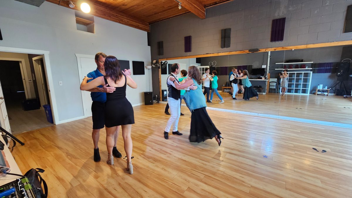 Several couples practicing together across a dance studio