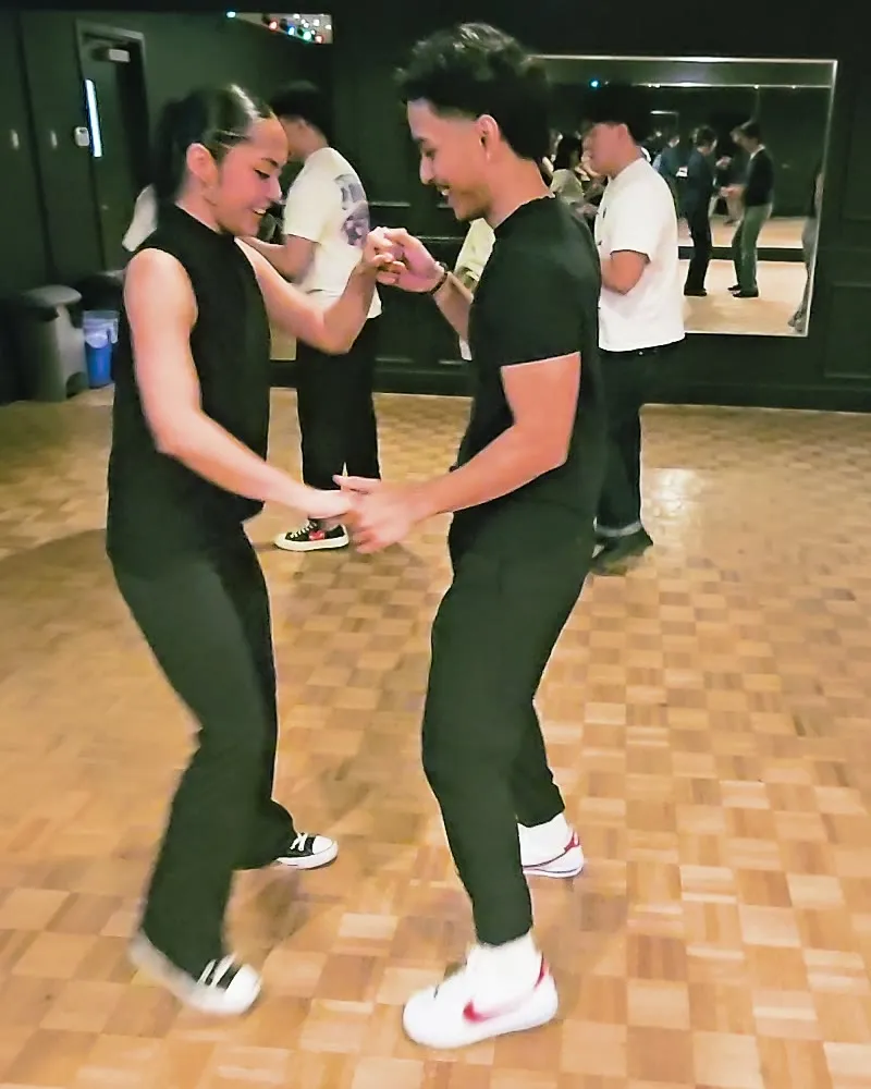 A smiling couple practicing partner dance in the studio