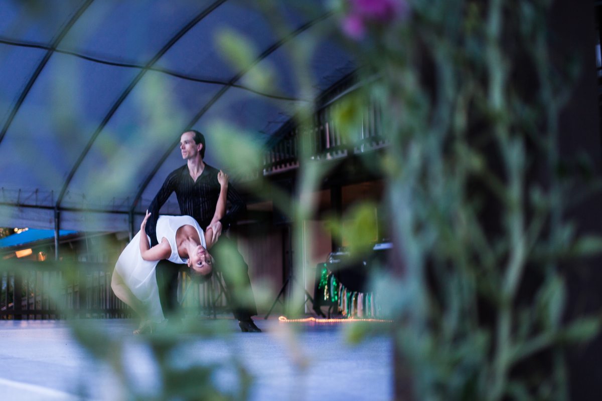 Two partners performing a supported dip beneath an outdoor pavilion