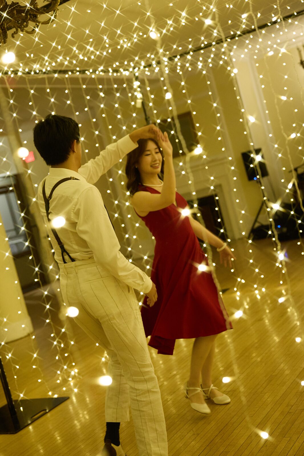 Wedding couple dancing beneath warm lights