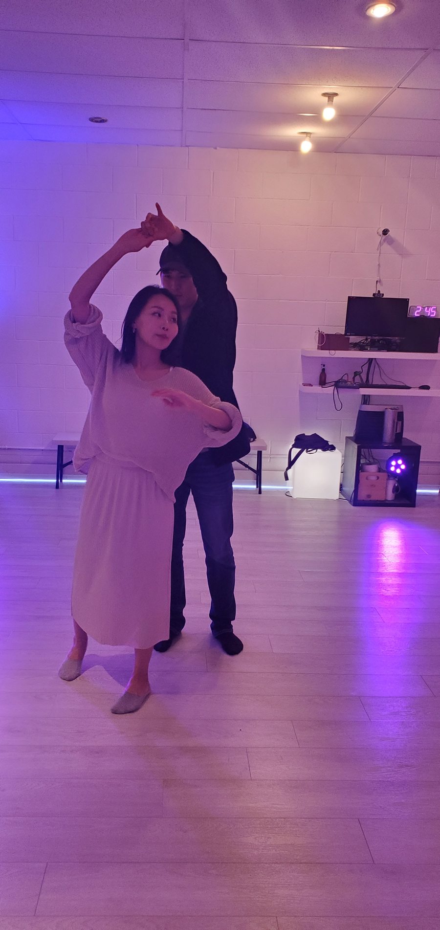 Two partners moving through an underarm turn in a purple-lit room