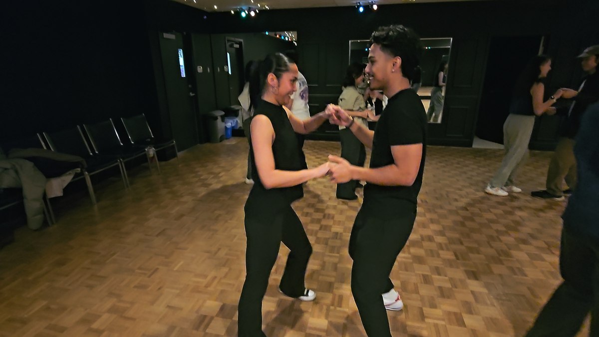Two partners smiling while practicing an open dance hold